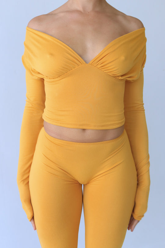Mustard yellow off-shoulder top and leggings set on a light blue background